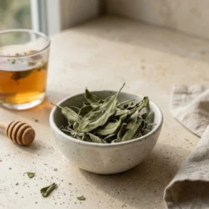 Dried sage leaves with herbal tea cup on warm stone surface in soft natural light