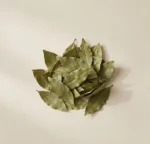 Whole dried bay leaves arranged organically on warm neutral beige surface