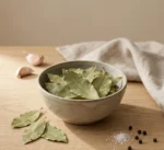 Bay leaves in a handmade ceramic bowl on warm beige background with soft natural daylight