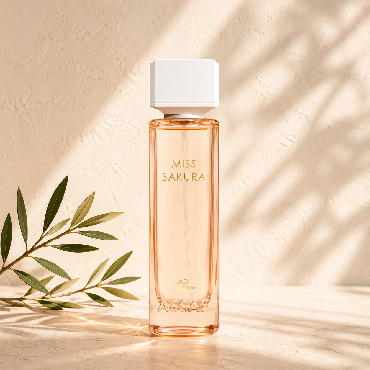 1-assaf-miss-sakura-hero Hero Image: Assaf Miss Sakura Eau de Parfum for Women on a warm limestone surface with a delicate olive branch and soft natural daylight.