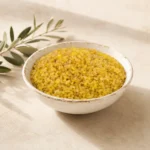Premium Coarse Bulgur Wheat in an aged white ceramic bowl on a warm neutral DARLEVANT background with soft natural daylight and olive branch accents.