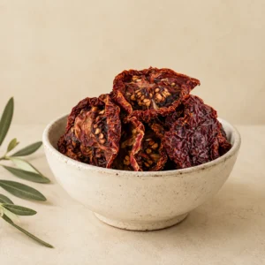 Premium Jordanian sun-dried tomatoes in an aged white ceramic bowl with visible seeds, natural wrinkles, and rich red color on a warm neutral background.