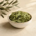 Premium Senna Leaves Herbal Infusion 250g in an artisanal white ceramic bowl with an olive branch on a warm neutral background, showcasing whole senna leaves with natural texture and traditional botanical character.
