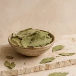 Dried bay leaves presented in a handcrafted ceramic bowl on natural limestone in a refined pantry setting