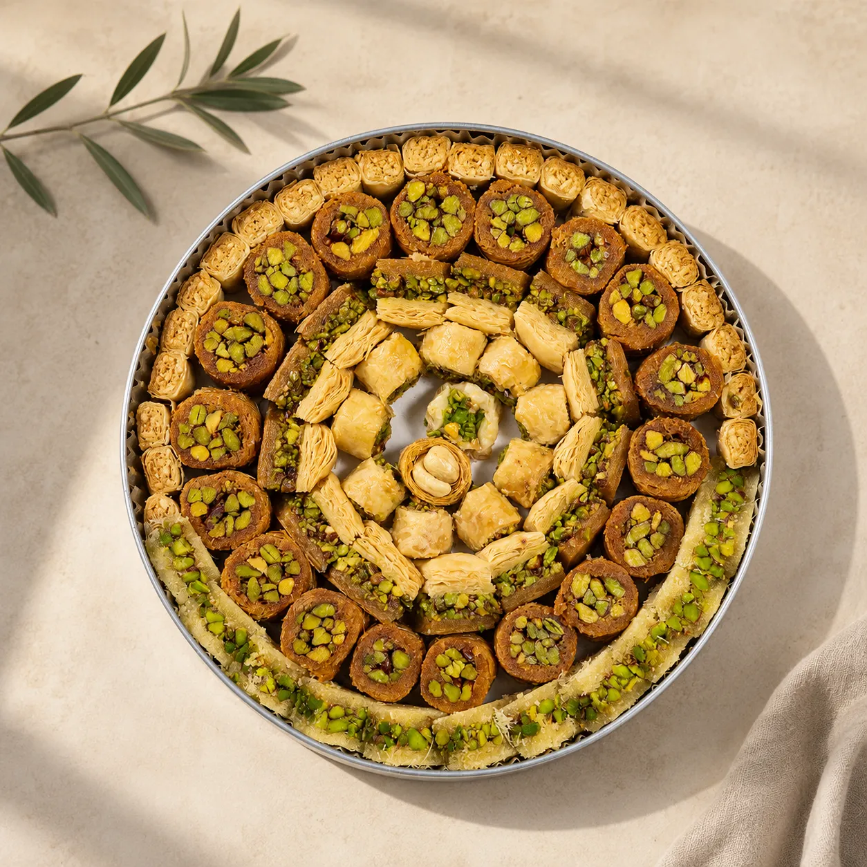 1habibah-mumtaz-assorted-arabic-sweets-signature Image 1 – Signature Traditional Levantine assorted Arabic sweets arranged in a round tray with pistachio-filled pastries, photographed in soft natural daylight against a warm neutral background.