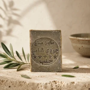 Traditional Aleppo Laurel Soap handcrafted bar with olive branch on natural stone in warm daylight inspired by Levantine heritage rituals