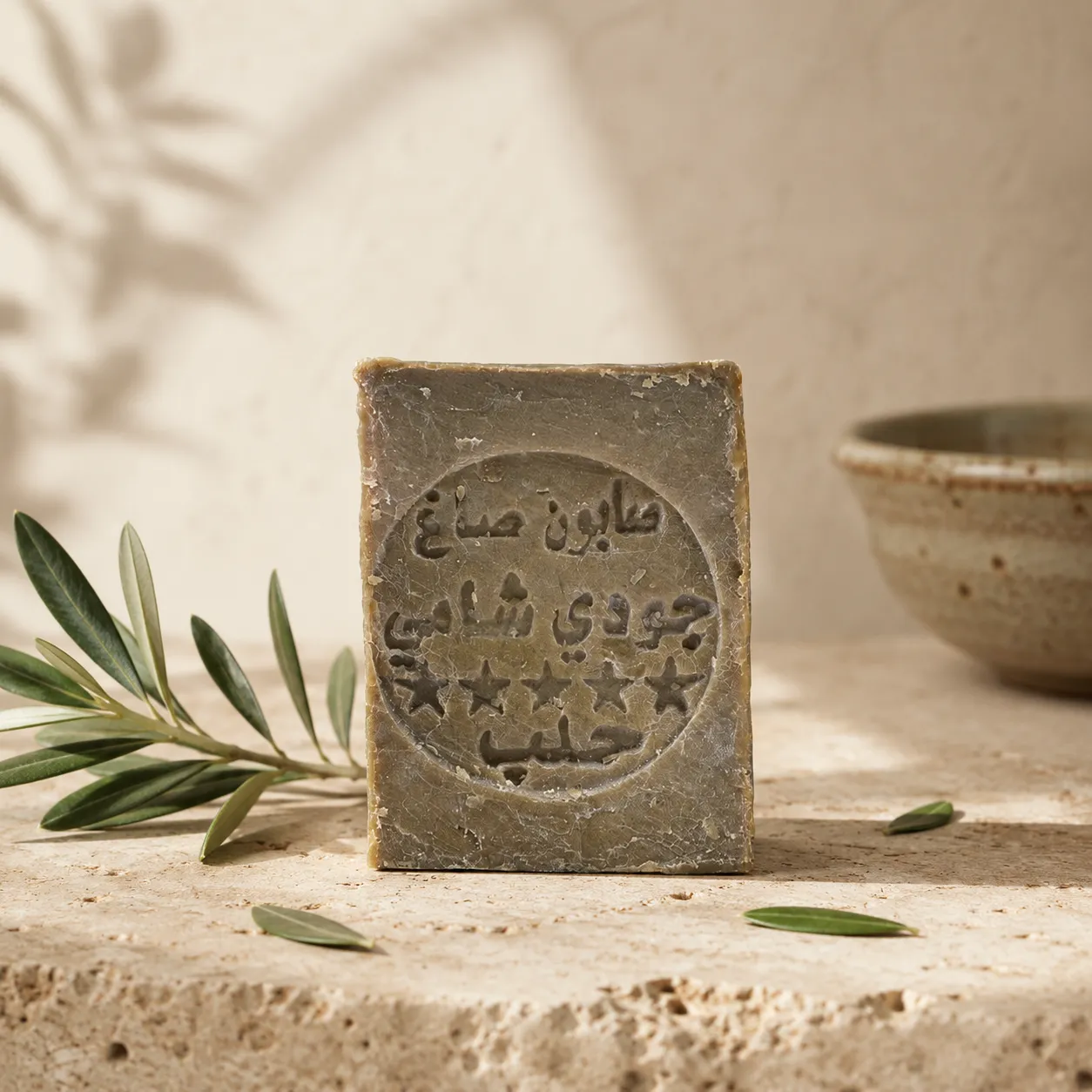 1traditional-aleppo-laurel-soap-set-of-3-hero Traditional Aleppo Laurel Soap handcrafted bar with olive branch on natural stone in warm daylight inspired by Levantine heritage rituals