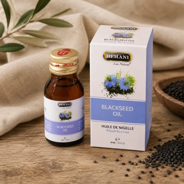 Hemani Black Seed Oil 30ml bottle with original retail box displayed on natural oak wood with black seeds and soft linen details.