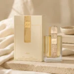 Lattafa Angham Eau de Parfum 100ml bottle and original box styled with soft ivory linen and warm neutral textures in natural afternoon light.