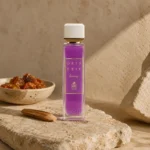 ASSAF Gris Erik Eau de Parfum bottle beside amber resin and sandalwood on natural stone in a warm earthy luxury fragrance setting