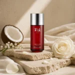 Assaf Risk Comete Eau de Parfum bottle with white rose, lily of the valley, and coconut on layered travertine surfaces in an editorial luxury setting.