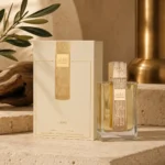 Lattafa Angham Eau de Parfum 100ml bottle with original box displayed on warm limestone surfaces with subtle brass accents and olive wood textures.