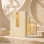 Lattafa Angham Eau de Parfum 100ml bottle and original box in a contemporary editorial setting with curved plaster forms and layered neutral textures.